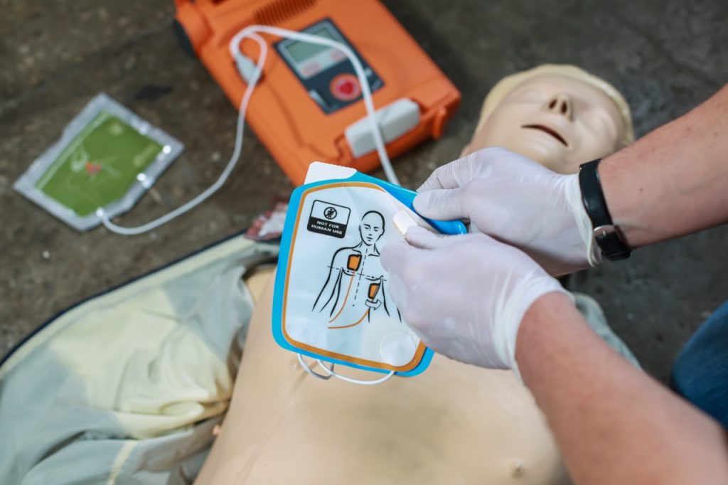 CPR instructor placing AED on training dummy during HeartSaver CPR course